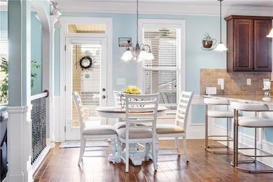 Dining area with ornamental molding, dark wood finished floors, and a chandelier
