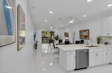 Kitchen with a peninsula, recessed lighting, stainless steel dishwasher, white cabinetry, and light stone counters