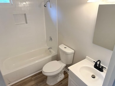 Full bath with toilet, wood finished floors, bathtub / shower combination, and vanity