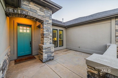 Entrance to property with stone siding, stucco siding, and a patio