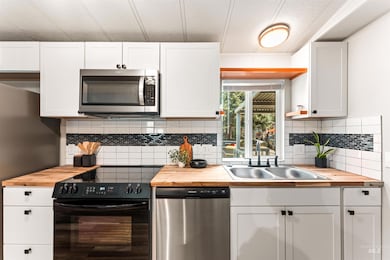 Kitchen featuring butcher block countertops, stainless steel appliances, and white cabinets