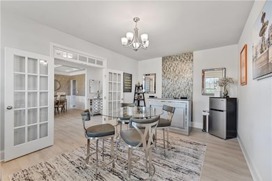 Dining space featuring light wood-type flooring, a chandelier, and french doors