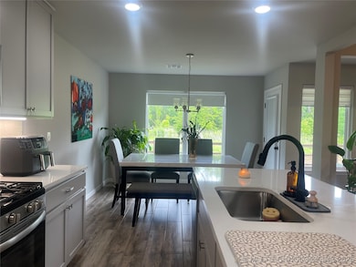 Kitchen with a sink, stainless steel range with gas stovetop, light countertops, dark wood finished floors, and recessed lighting