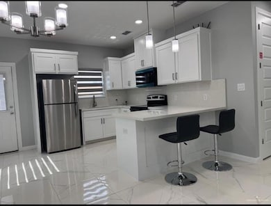 Kitchen featuring freestanding refrigerator, electric range oven, baseboards, a peninsula, and a sink