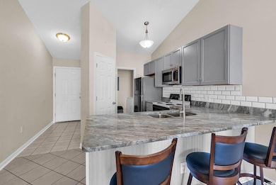 Kitchen with backsplash, a breakfast bar area, a peninsula, light tile patterned floors, and appliances with stainless steel finishes