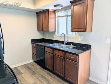Kitchen featuring dishwasher, light wood-style floors, and dark solid surface counters