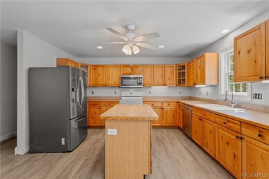Kitchen featuring appliances with stainless steel finishes, a center island, ceiling fan, sink, and light hardwood / wood-style flooring