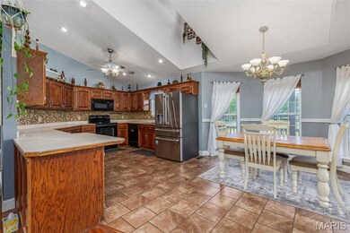 Kitchen with black appliances, a textured ceiling, a chandelier, decorative backsplash, and a peninsula