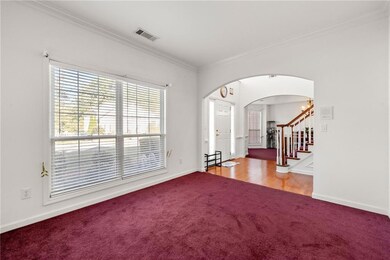 Carpeted spare room featuring stairway, crown mold