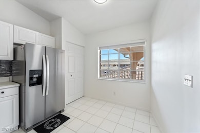 Kitchen with stainless steel fridge with ice dispenser, white cabinetry, and light countertops