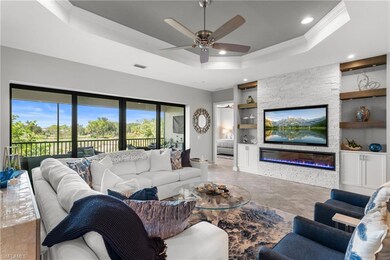 Living area featuring crown molding, built in shelves, a tray ceiling, ceiling fan, and recessed lighting