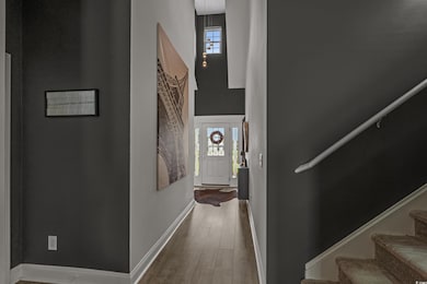 Corridor with wood finished floors, stairs, plenty of natural light, and a high ceiling