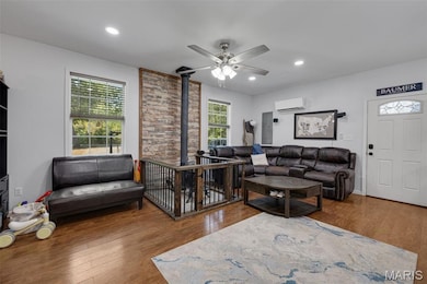 Living area featuring wood finished floors, a wood stove, a ceiling fan, recessed lighting, and a wall mounted air conditioner