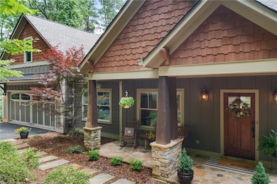 Property entrance with board and batten siding, covered porch, and a shingled roof