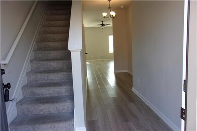 Stairway featuring wood finished floors, a ceiling fan, a chandelier, and baseboards