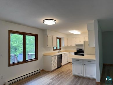 Kitchen featuring a baseboard radiator, electric range, black dishwasher, light wood-type flooring, and light countertops