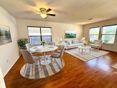 Dining area with healthy amount of natural light, a textured ceiling, wood finished floors, and ceiling fan