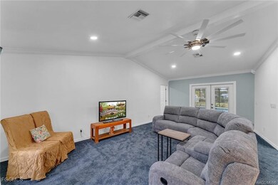 Carpeted living area with ornamental molding, a ceiling fan, french doors, and recessed lighting