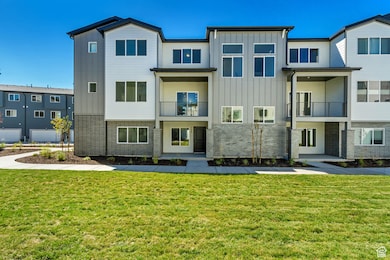 Back of house featuring brick siding, board and batten siding, a balcony, and a lawn