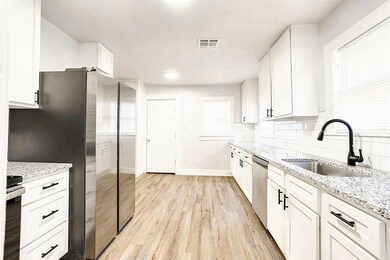 Kitchen with light wood-type flooring, light stone