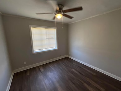 Spare room with ceiling fan, baseboards, dark wood