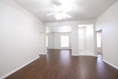 Empty room with dark hardwood / wood-style floors and ceiling fan with notable chandelier
