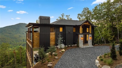 View of front facade with a chimney, a mountain view, and a wooded view