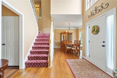 Entrance foyer with stairway, light wood-style flooring, and a high ceiling