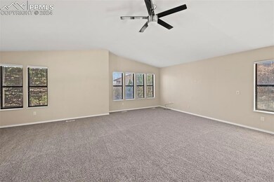 Carpeted spare room with ceiling fan and vaulted ceiling