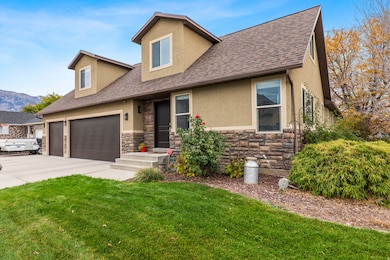View of front of house with a shingled roof, stucco siding, stone siding, concrete driveway, and a front lawn