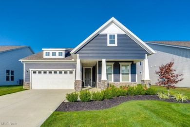 View of front of house with stone siding, a porch, a front lawn, driveway, and a shingled roof