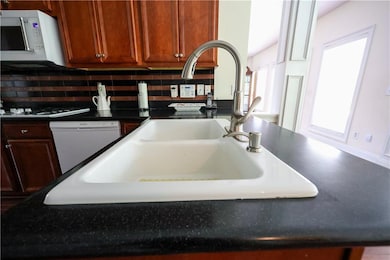 Kitchen view of white appliances, backsplash, and dark countertops