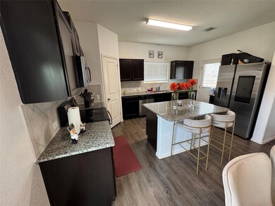 Kitchen with tasteful backsplash, light stone countertops, appliances with stainless steel finishes, dark wood-type flooring, and a textured ceiling