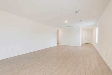 Empty room with visible vents, light wood-style flooring, and baseboards