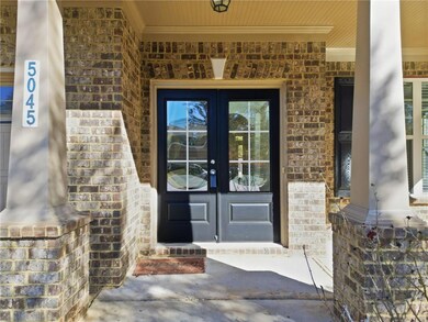 View of exterior entry with brick siding, a porch, and french doors