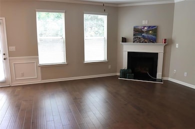 Unfurnished living room with a fireplace with raised hearth, dark wood-style floors, and ornamental molding