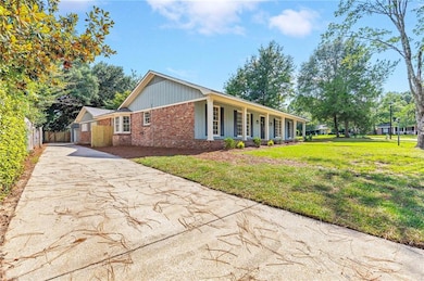 View of front of property featuring driveway, brick siding, covered porch, and board and batten siding