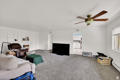 Carpeted living room featuring ceiling fan and a baseboard radiator
