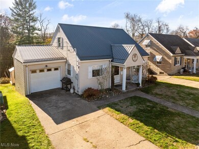View of front of home with driveway, an attached garage, a metal roof, and a front lawn