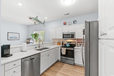 Kitchen featuring stainless steel appliances, a sink, tasteful backsplash, white cabinets, and recessed lighting