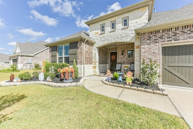 Covered front porch offers space for outdoor seating and relaxation. Brick and stone façade adds timeless character to the entryway.