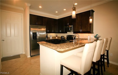 Kitchen with stainless steel appliances, light stone countertops, a peninsula, dark brown cabinets, and recessed lighting