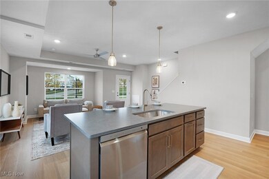 Kitchen featuring stainless steel dishwasher, a kitchen island with sink, pendant lighting, light wood-style flooring, and open floor plan