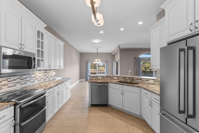 Kitchen with stainless steel appliances, decorative light fixtures, recessed lighting, a chandelier, and light stone countertops