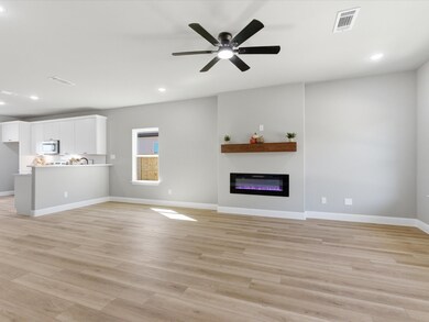 Unfurnished living room with light wood finished floors, recessed lighting, ceiling fan, and a glass covered fireplace