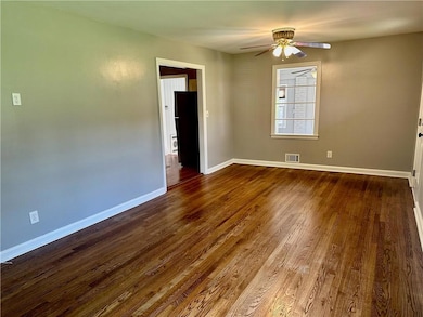 Spare room featuring a ceiling fan, dark wood-type flooring, and baseboards