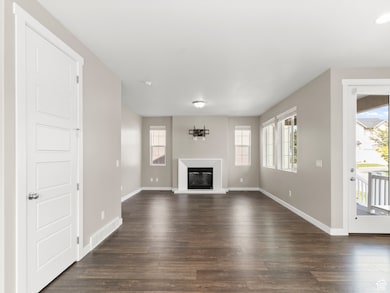 Unfurnished living room featuring dark wood-type flooring, a glass covered fireplace, and plenty of natural light