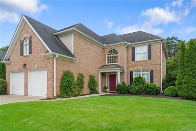 Colonial home with brick siding, a front yard, and concrete driveway