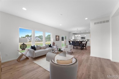 Living room with recessed lighting, light wood-style floors, and a chandelier