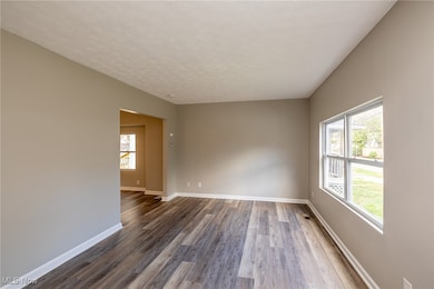 Living room featuring a textured ceiling and luxury vinyl plank floors and large picture window for natural light.